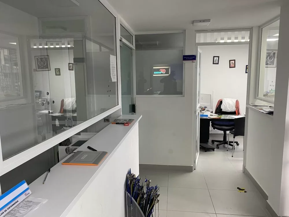 Pasillo de recepción con la ventanilla de atención y los consultorios de la sede de La Castellana